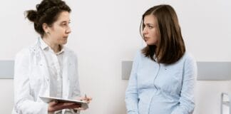 Jak rozmawiać z personelem medycznym o swoich granicach przy porodzie, by czuć się bezpiecznie, a jednocześnie zachować otwartość na konieczne interwencje Kobieta w ciąży rozmawia z lekarką w gabinecie medycznym