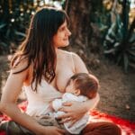 Mama karmiąca piersią niemowlę na kocu na świeżym powietrzu latem