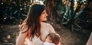 Bolesne brodawki przy karmieniu piersią – skuteczne sposoby na ulgę Mama karmiąca piersią niemowlę na kocu na świeżym powietrzu latem