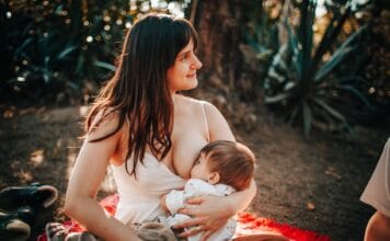 Mama karmiąca piersią niemowlę na kocu na świeżym powietrzu latem